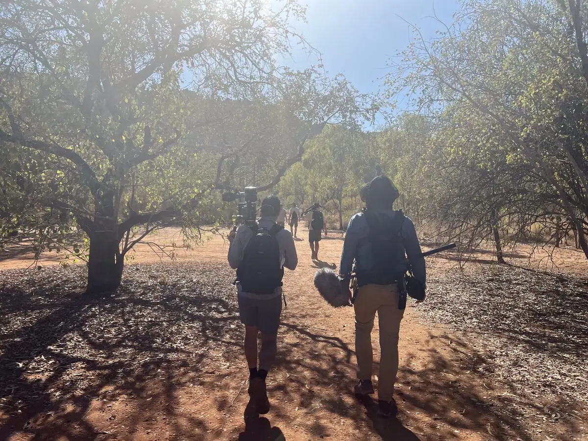 Film crew with camera and sound gear walking into a remote location