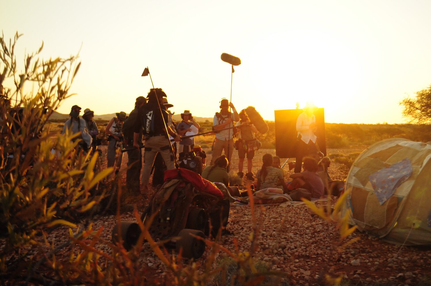 Documentary film crew filming on location in the outback at sunset