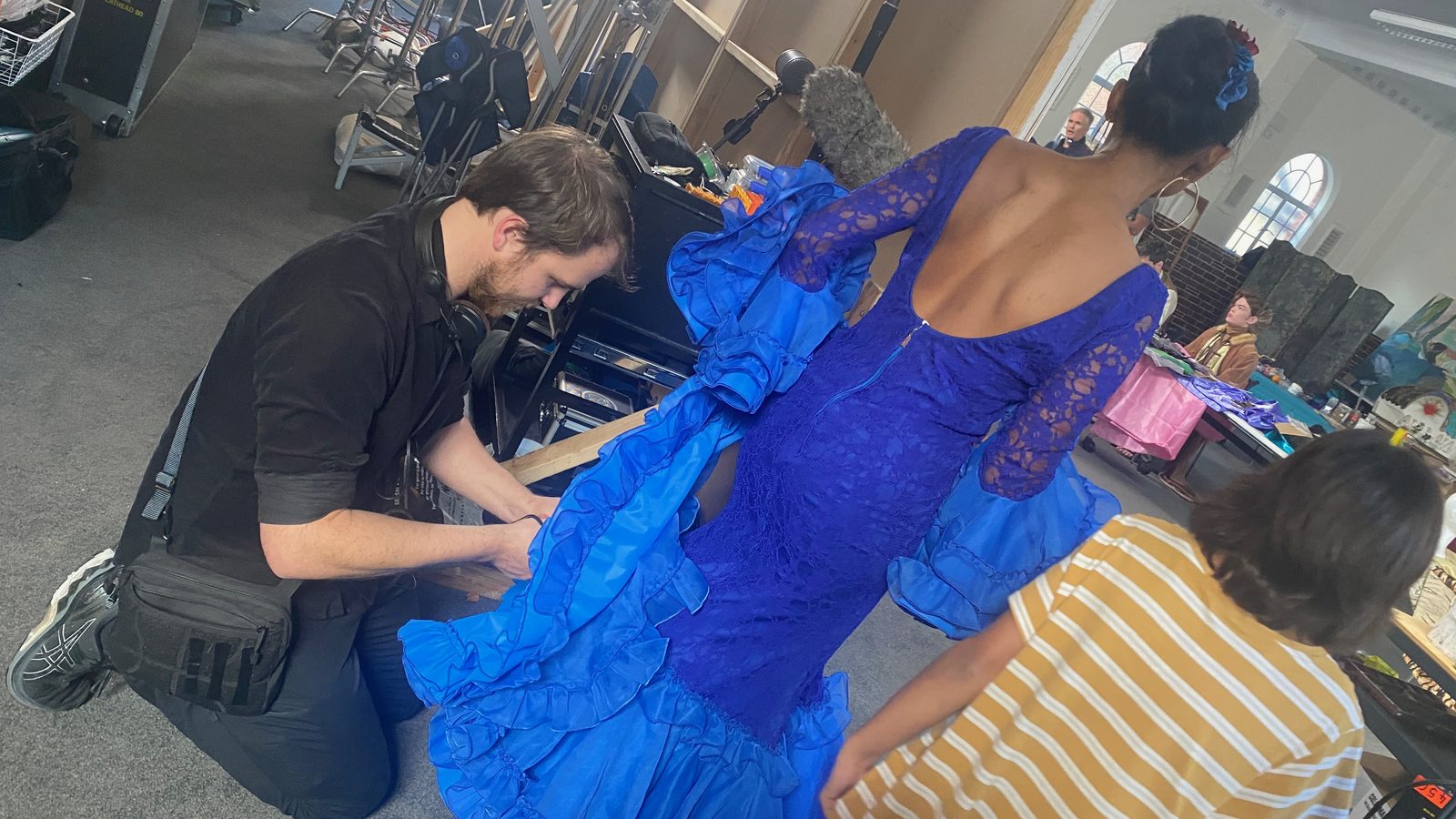 Location sound recordist Richard Hubbard fitting a radio lavalier mic to a performer in a blue flamenco dress on set